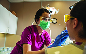 Nurse and patient with masks in hospital setting.