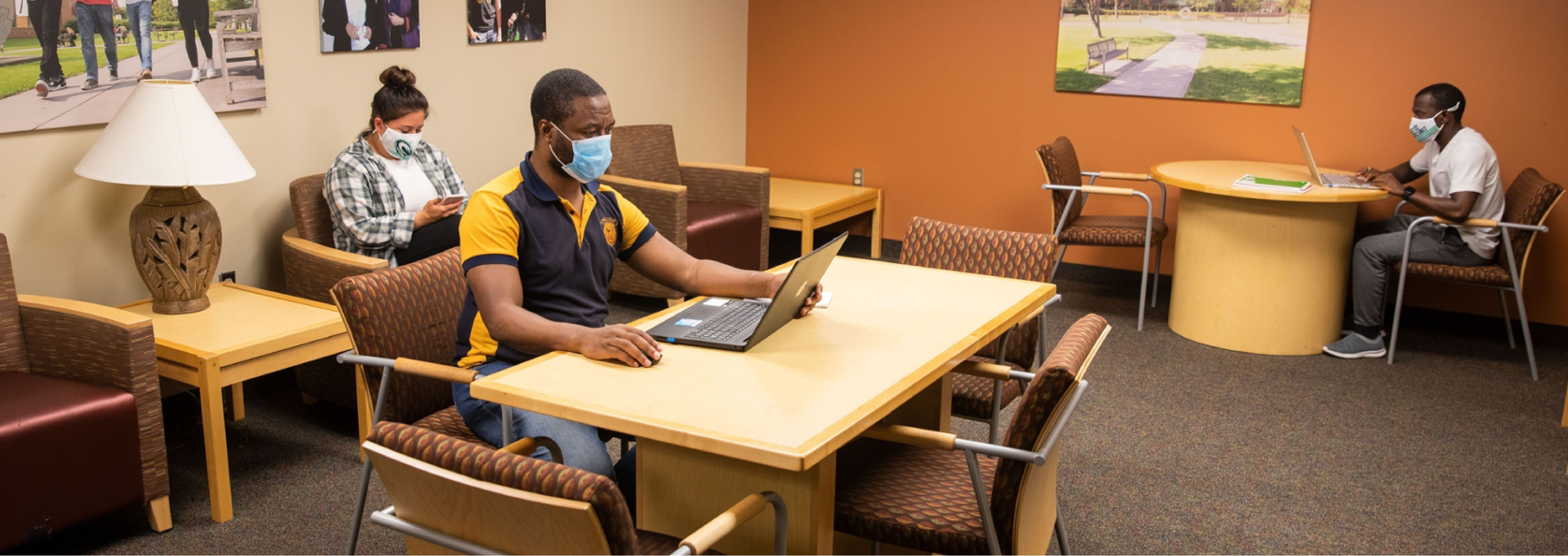 Students sitting in a room using laptops and mobile devices